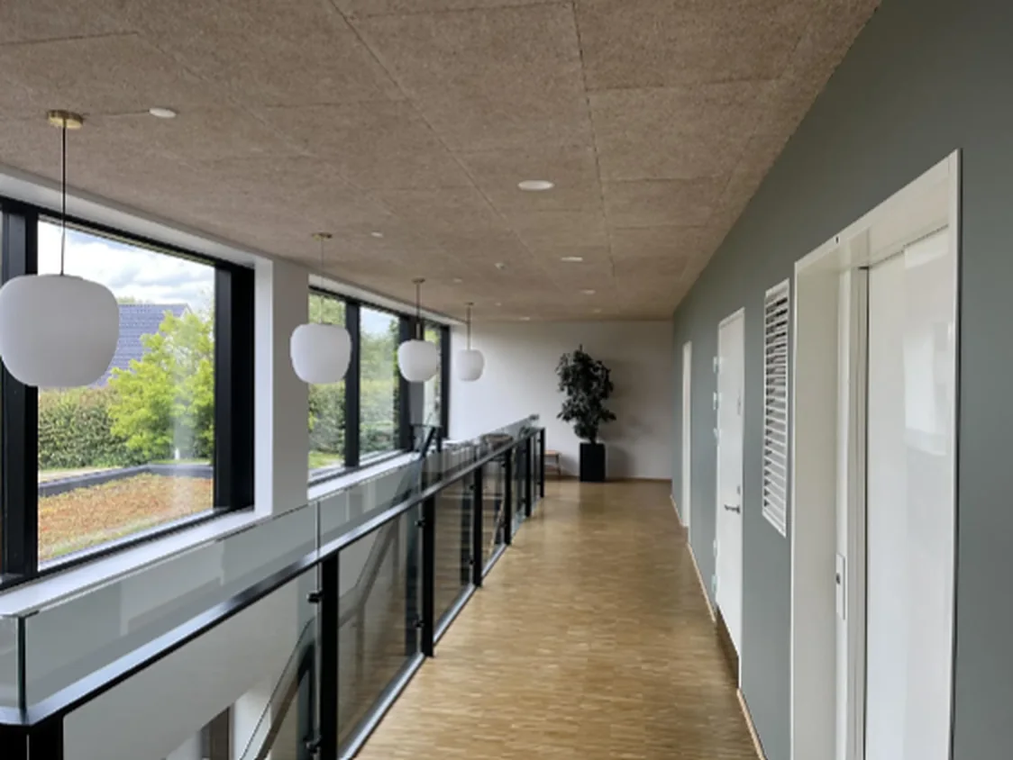 Runde pendler over et gangareal med glasværn og troldtekt-loft